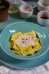Ravioli with mushrooms and with bacon and sour cream sauce. Blue wooden table, blue plates.