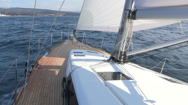 On board view of main deck of a sailing boat with full sails open.