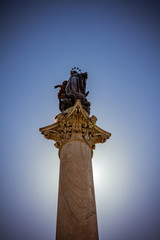 Statue on column in rome backlit by the sun