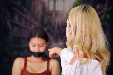 Young mad american blonde woman, exhorting to a latin woman to leave the country, using her arm and...
