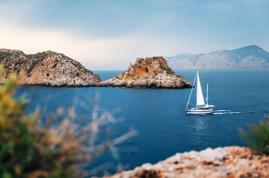 Sailboat with german flag are sailing at Mediterranean sea between cliffs and rocks against the stormy sky, Santa Ponsa, Mallorca, Spain