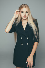 Beautiful female model in black dress on gray background
