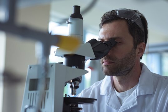 University student doing experiment on microscope in laboratory