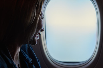 Fototapeta na wymiar Young beautiful woman looking into the airplane window