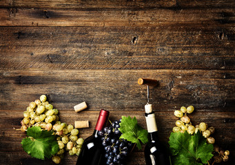 Wine bottles with grapes on wooden rustic background with copy space. Red and white wine. Top view.