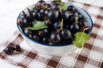 Fresh blackberries (black currant) in ceramic bowl on white wooden table, selective focus