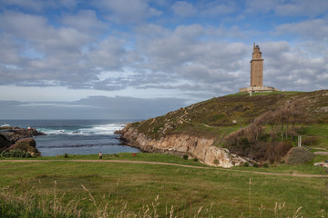 Fototapeta na wymiar Hercules Tower Lighthouse in Coruna Spain on a sunny day with blue sky and clouds on top of the hill