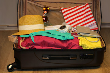 Collected suitcase for travel. Suitcase in open view closeup with things to rest on a wooden background