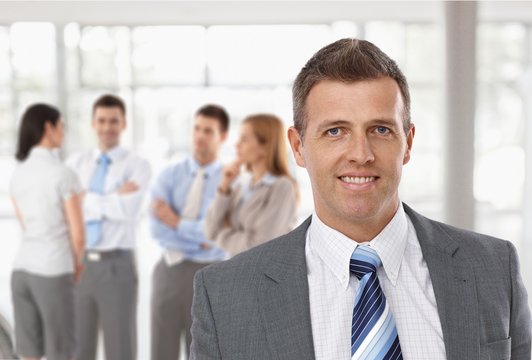 Middle-aged businessman in front of colleagues