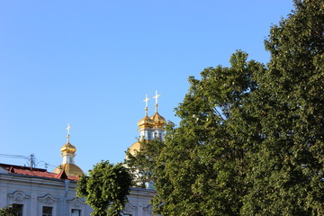 Fototapeta na wymiar three golden domes on the background of the sky and greenery
