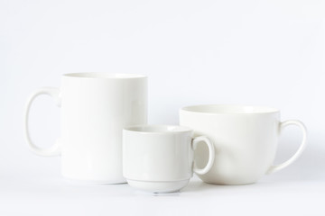 Three white cups of different size and design, clean tea mug and coffee cups