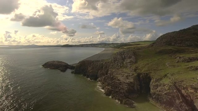 Panning aerial shot of the Welsh coast on a sunny day in the UK.