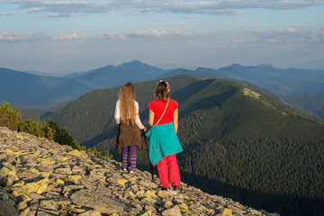 Mom and daughter stand on the edge of cliff