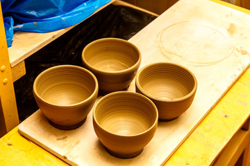 A pottery. white bowls and plates are on shelves of the cupboard