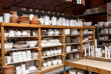 A pottery. white bowls and plates are on shelves of the cupboard
