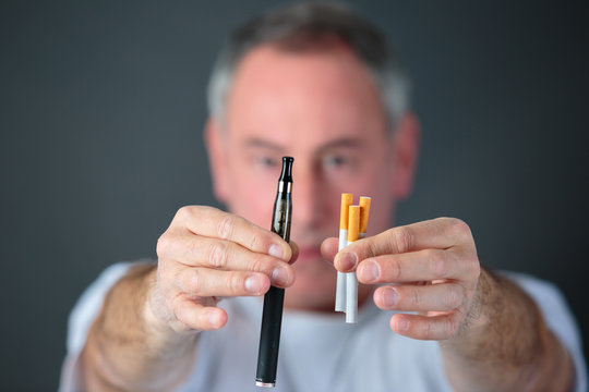 man comparing classic tobacco cigarette and electronic cigarette or vaporizer