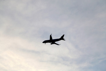 Fototapeta na wymiar Plane silhouette on a cloudy sky. 