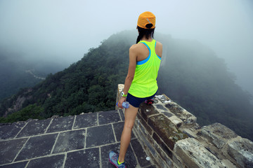 woman trail runner haves a rest at great wall on the top of mountain