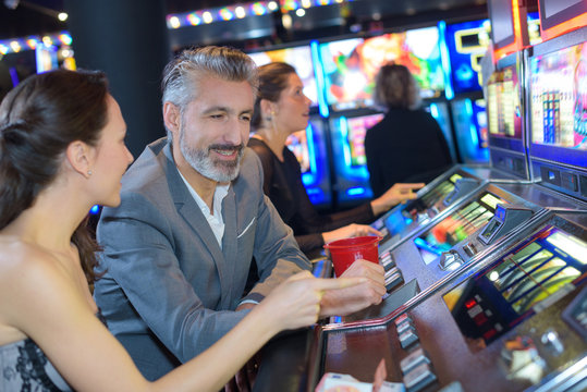 couple playing slot machines in casino