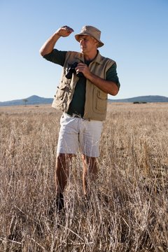 Man With Binocular Shielding Eyes On Landscape