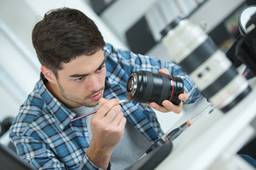 young attractive man fixing dslr camera lense