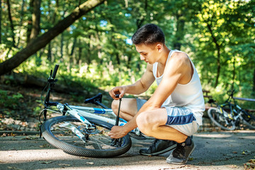 Obraz premium Man pumping wheel of a bicycle. The concept of cycling and a healthy lifestyle.