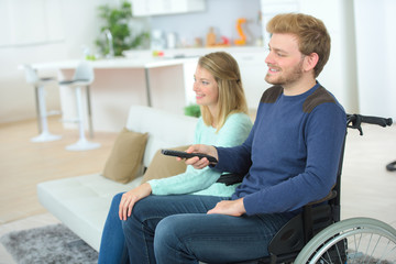 couple watching tv at home man sitting on wheelchair