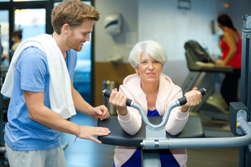 female senior in the gym assisted by the trainer