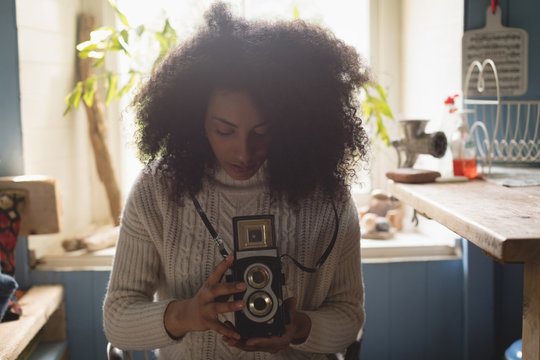 Woman looking at pictures on vintage camera at home