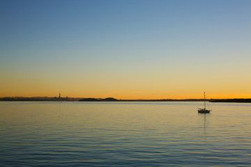 Fototapeta na wymiar Golden and orange light closes the day over Auckland and the serene Waitemata Habour, New Zealand