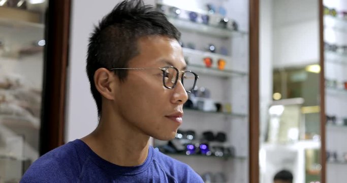 Asian man trying glasses in optical shop