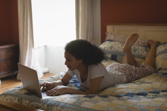 Woman lying and using laptop on bed