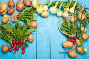 Raw radishes and potatoes on a blue wooden background
