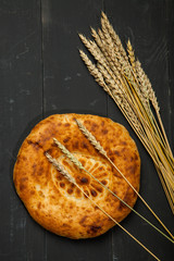 Wheat and flat cake on a black wooden background