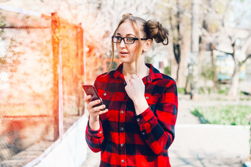 the girl is holding the phone. stands on the street. I read something on the Internet