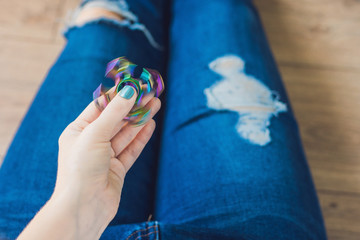 Girl teenager in holey jeans holds in hands and plays with spinner