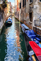 Gondolas and small boats on a narrow canal in Venice