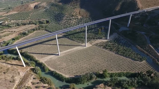 1080p Aerial, Flight over a highway bridge and down river village and olive orchards, Andalucia, Spain. Staright rows of olive trees and high rise bridge with going on cars. Way to Cordoba