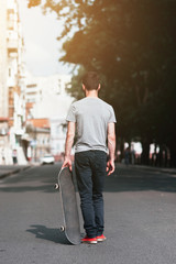 Young hipster man moves off with skateboard. First step in skateboarding sport challenge, failure and frustration, bad day for win