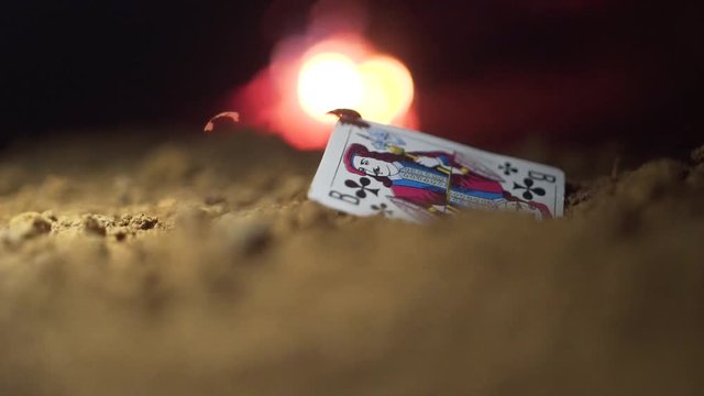 Games card Jack in the sand. Footage. Beetle crawling on card is Jack, fire on the background. Abstract playing card on ground. Old playing card Jack
