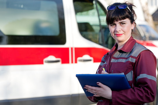 Paramedic female with clipboard at emergency car