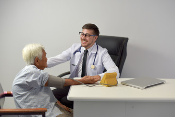 Physician checking blood pressure of ill senior woman