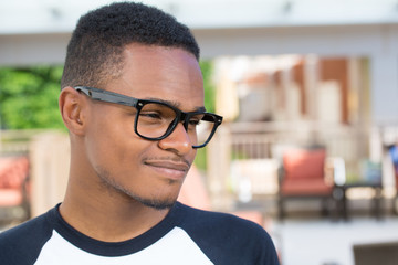 Closeup headshot portrait of fine young man with big glasses, undergrad student, smiling, isolated on outside outdoors background.