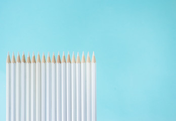 Business concept - lot of white pencils and stand on blue paper background like a fence. It's symbol of teamwork.