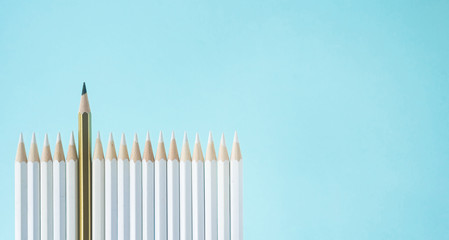 Business concept - lot of white pencils and one color pencil stand on blue paper background like fence. It's symbol of leadership, teamwork, united and communication.