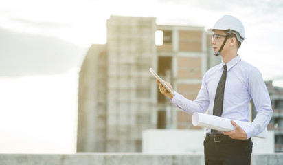 smiling young architect or engineering builder in hard hat with tablet over group of builders at...