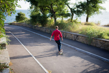 stylish skater in red shirt and blue jeans ride downhill on longboard, summer active picture  