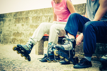 People friends putting on roller skates outdoor.