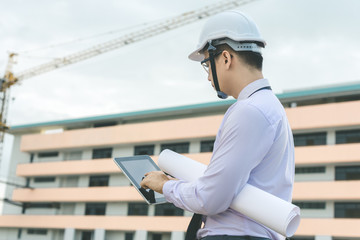 smiling young architect or engineering builder in hard hat with tablet over group of builders at...