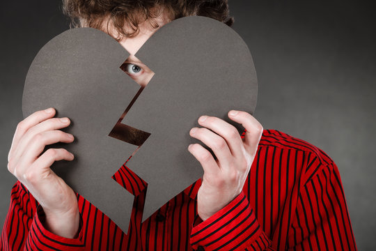 Young depressed man covered by broken heart.